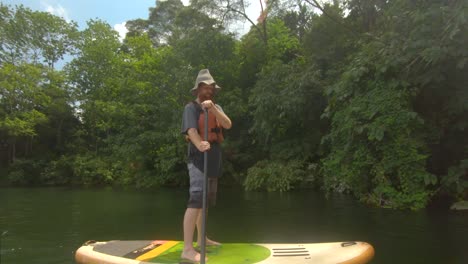 A-bearded-ginger-man-out-on-the-banks-of-the-river-Nile-in-tropical-Africa-on-a-stand-up-paddle-board