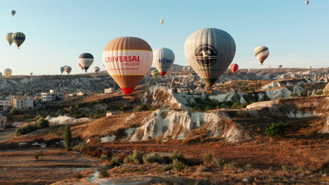 Early-morning-hot-air-ballooning-over-the-prehistoric-landscape-of-Goreme-Cappadocia,-Turkey