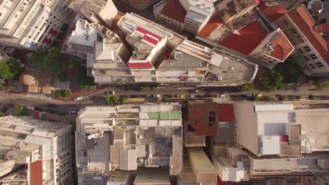 aerial-drone-top-shot-of-rooftops-urban-center-of-Athens-small-road-downtown-traffic-capital-of-Greece-sunny-day-establishment-generic-shot-shapes-geometry-small-buildings