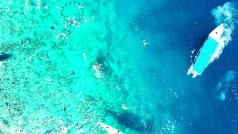 Grupo-De-Turistas-Explorando-Hermosos-Arrecifes-De-Coral-En-Aguas-Cristalinas-De-Color-Turquesa,-Barco-Turístico-Flotando-En-El-Mar-En-Calma