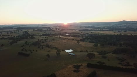 Aerial-footage-looking-into-the-sun-of-a-rural-landscape-near-Tylden,-central-Victoria,-Australia