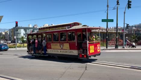 The-famous-San-Francisco-Trolley-filled-with-tourists-heading-down-a-hill-on-Columbus-Street-towards-the-waterfront
