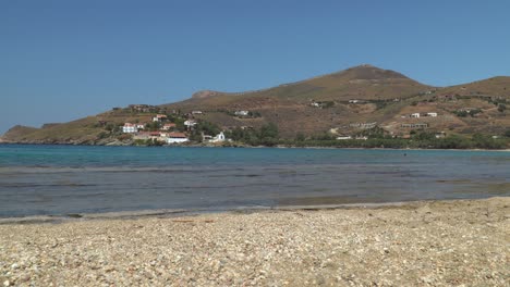 Vista-Estática-Sobre-La-Playa-Rocosa,-El-Océano-Y-Las-Colinas-Con-Casas-En-El-Fondo