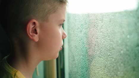 Kind-Bei-Regen-Durch-Ein-Fenster-Schauen