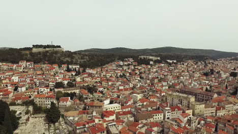 Flying-over-the-city-of-Sibenik,-panoramic-view-of-the-old-town-center-and-coast