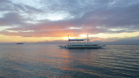 Aerial-view-of-a-Spider-boat-in-Moalboal-Beach-at-the-sunset,-Cebu,-Philippines