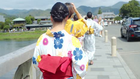 Beautiful-girl-wearing-a-traditional-kimono-taking-a-picture-of-the-river-walking-over-the-brige-in-Kyoto,-Japan-soft-lighting-slow-motion-4K