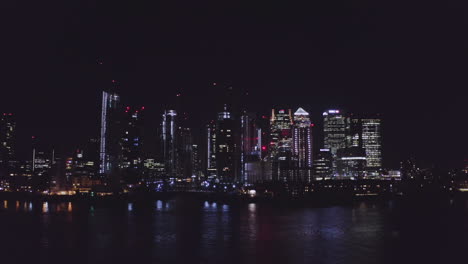 Aerial-View-of-London-Financial-District-at-night-from-the-river-Thames