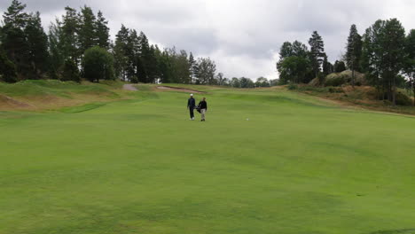 Jugadores-De-Golf-Caminando-Pasan-El-Campo-De-Golf-En-Suecia,-Vista-De-órbita-Aérea