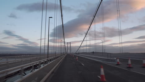 Motion-shot-from-a-vehicle-crossing-a-Forth-road-bridge-with-wonderful-sunset-light-and-clouds-in-Edinburgh,-Scotland