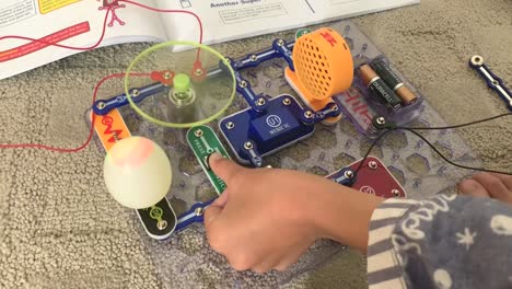 Small-hands-testing-out-the-fan-and-colored-lights-button-of-the-Snap-Circuit-Jr