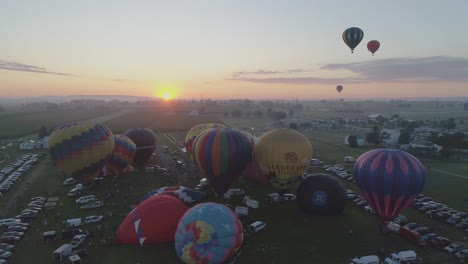 Aerial-View-of-a-Sunrise-Hot-Air-Balloons-Taking-Off-at-a-Balloon-Festival-on-a-Clear-Summer-Morning