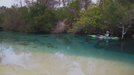 Two-elderly-people-are-enjoying-kayaking-and-paddling-their-kayaks-through-the-magical-clear-blue-water-of-Weeki-Wachee-State-Park-Spring-River