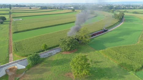 An-Aerial-View-of-a-Steam-Train-no-611-Puffing-Smoke-Through-Farm-Countryside-on-a-Sunny-Summer-Day-with-Green-Fields