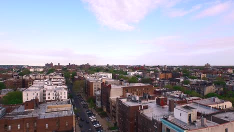 Aerial-flyover-of-Brooklyn-rooftops-with-beautiful-blue-pink-sky-after-sunrise-4K