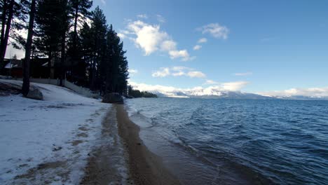 Calm-waves-on-a-winter-day-in-Lake-Tahoe-California-with-snow-on-the-ground,-Handheld-stable-shot
