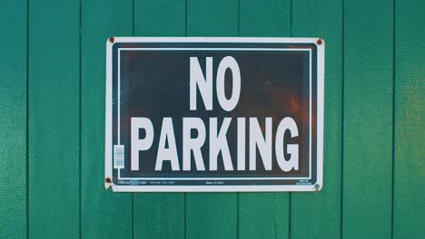 Sign-saying-no-parking-fixed-to-green-timber-wall