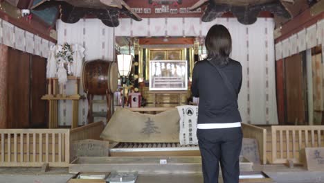alone-woman-praying-shinto-temple,-tracking-dolly-in-shot