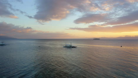 Aerial-view-of-a-Spider-boat-in-Moalboal-Beach-at-the-sunset,-Cebu,-Philippines