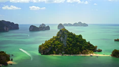 top-view-of-small-overgrown-island-in-thailand,-longtail-boat-driving-away