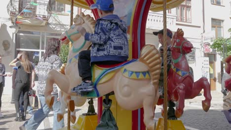 Children-ride-on-a-small-children's-carousel-with-horses