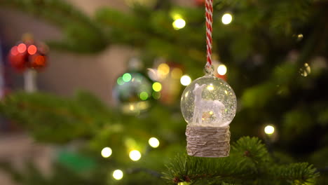 Kristallkugel-Schneeball-Mit-Weißen-Schafen-Und-Schnee-Im-Inneren,-Der-An-Einem-Weihnachtsbaum-Hängt