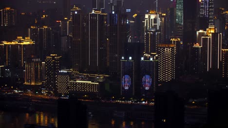 Skyline-of-the-city-at-night-showing-window-projection-on-buildings-by-the-Jialing-river,-Handheld-establishing-shot