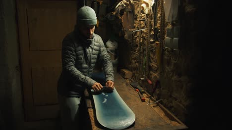 Man-starts-scraping-of-wax-of-a-snowboard