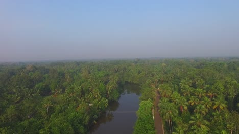 Aerial-shot-of-backwater-river-and-village-road,coconut-forest,blue-sky