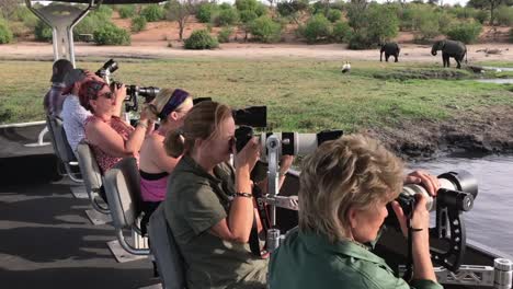 Los-Huéspedes-En-Un-Safari-Fotográfico-Toman-Fotografías-De-Elefantes-Desde-Un-Bote-Fluvial