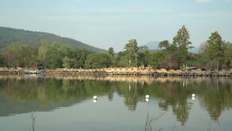Beautiful-Huay-Tung-Tao-Lake-in-Chiang-Mai-with-a-lush-mountain-backdrop,-displaying-the-straw-huts-on-the-lake-front