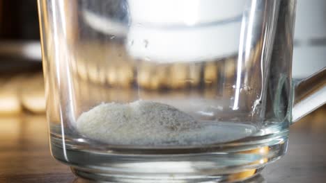 Pouring-magnesium-vitamin-powder-into-glass-cup-in-close-up-shot