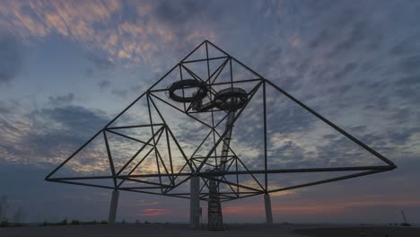 Sunrise-time-lapse,-Tetraeder-steel-pyramid-silhoette-against-colorful-clouds