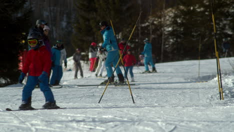 Ski-lessons-as-child-skis-in-and-out-of-foreground,-slow-motion