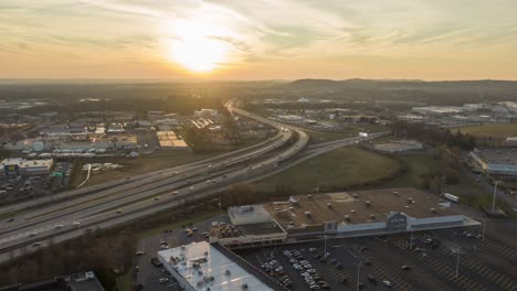 Aerial-hyperlapse,-rotation-reveals-shopping-centers-along-busy-highways-under-beautiful-sunset