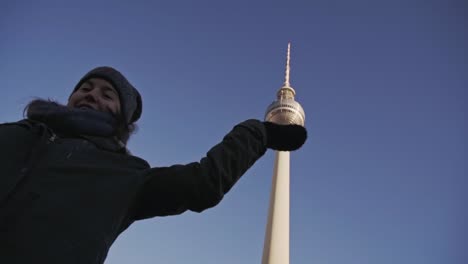 Girl-posing-for-photo-with-sphere-on-top-of-Berlin-TV-tower,-low-angle-shot