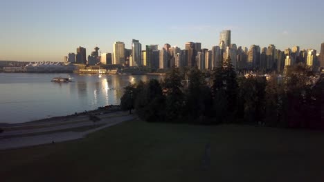 Downtown-Skyline-Of-Coal-Harbour-Seen-From-Brockton-Point-At-Stanley-Park-During-Sunrise-Surrounded-By-The-Calm-Waters-Of-Burrard-Inlet-In-Vancouver,-British-Columbia,-Canada