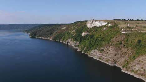 Aerial-View-of-a-Cliff-Overlooking-a-River-on-a-Bright-Sunny-Day
