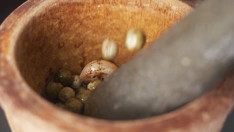 Filling-a-Mortar-and-Pestle-with-Chilies,-Garlic-and-Green-Peppercorns