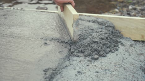 Tapping-flattening-fresh-cement-with-wooden-board