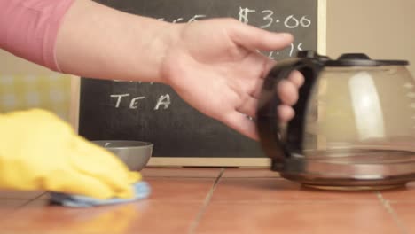 Hands-in-rubber-gloves-cleaning-down-cafe-table-medium-shot