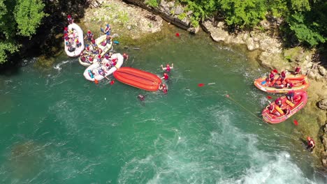 River-rafting-teams-after-going-down-Strbacki-Buk-waterfall-in-the-Una-river-getting-to-the-rocky-shore,-Aerial-top-view