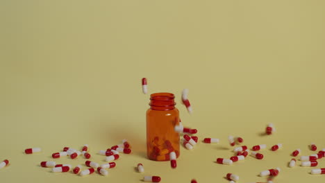 Weitschuss-In-Zeitlupe,-Während-Eine-Handvoll-Pillen-Auf-Eine-Offene-Tablettenflasche-Fallen