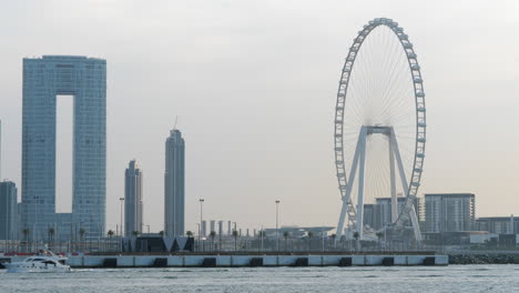 Luxury-yacht-cruising-in-front-of-Ain-Dubai-Ferris-wheel-and-cityscape