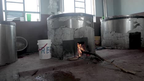 Bambara-Groundnut-woodfire-heated-boiling-metal-vat-steaming,-Handheld-low-shot