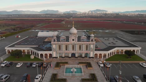 Drone-4K-Footage-front-facade-of-Sikh-temple-with-beautiful-elaborate-sculpture-symmetrical-architecture-in-the-middle-of-farmland-revealing-the-blueberry-fields-and-parking-lots-around-the-building