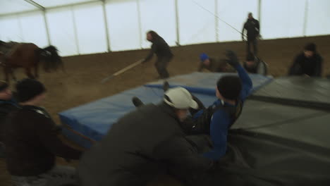 Stuntman-pulled-off-running-horse-by-jerk-vest-onto-stunt-pad-mat,-Slow-Motion