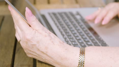 Nahaufnahme-Der-Hände-älterer-Frauen,-Während-Sie-Einen-Laptop-Bildschirm-Hält-Und-Auf-Dem-Trackpad-Scrollt