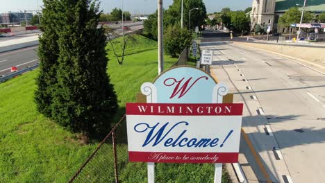 Welcome-to-Wilmington-sign-between-road,-aerial-pullback-shot