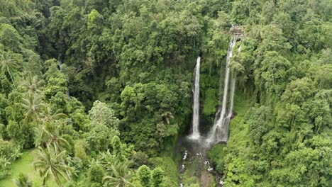 Slow-drawing-back-tracking-shot-of-tall-lush-jungle-waterfall